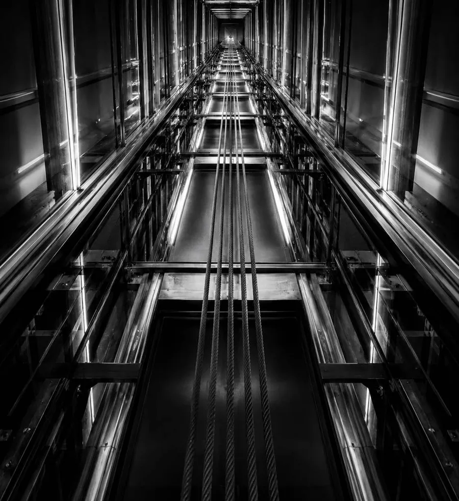 Looking up a glass lift shaft, in high-contrast black and white